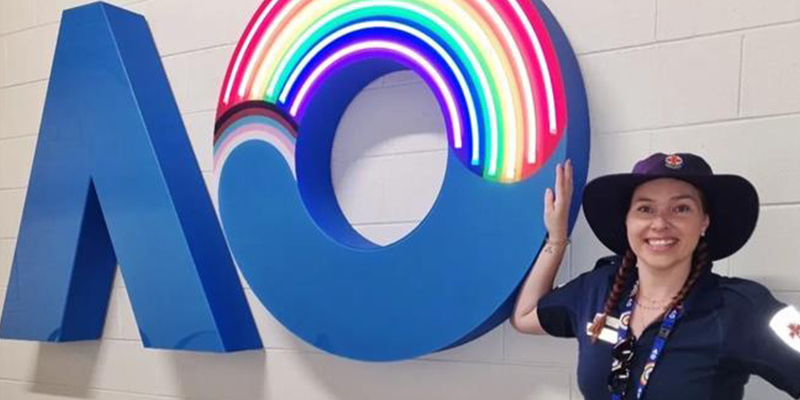 An Ambulance Victoria paramedic stands beside the Australian Open logo on a wall