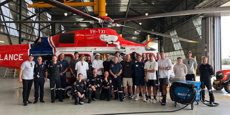 Carlton Football Club and AV staff stand in front of an AV helicopter