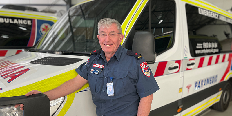 Paramedic Brain Pike standing proudly in front of an ambulance.