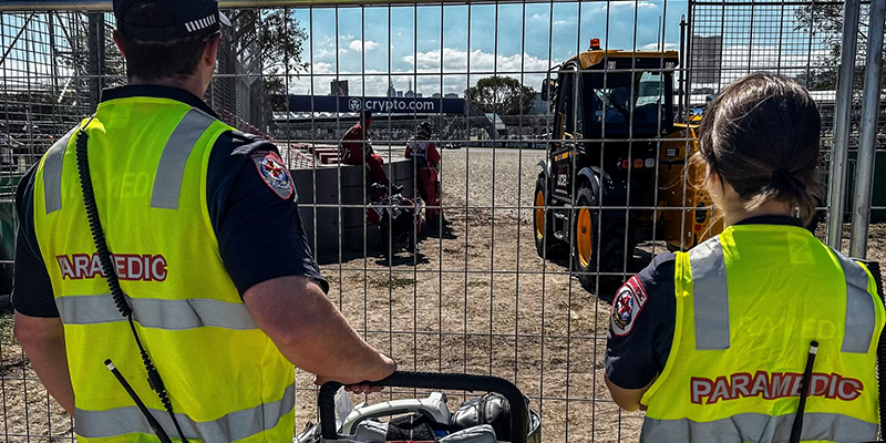 Two paramedics looking through a wire fence.