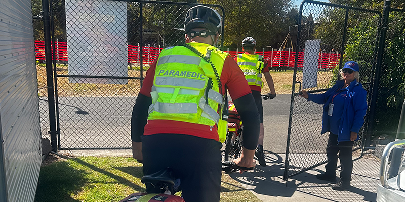 A paramedic on a bicycle peddling away from the camera.