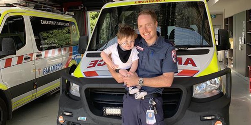Ambulance Victoria paramedic Jacob Every and son Finley standing in front of an ambulance