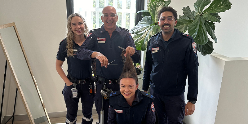 ALS paramedic Salvatore Primerano is holding a scissors and is ready to perform a hair cut on a colleague.