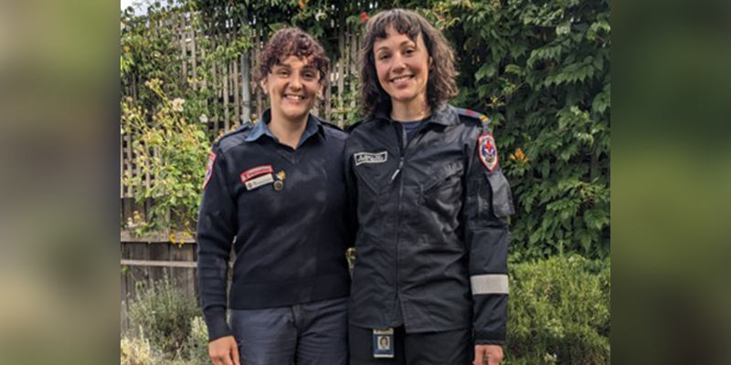 Two women stand together in Ambulance Victoria uniforms