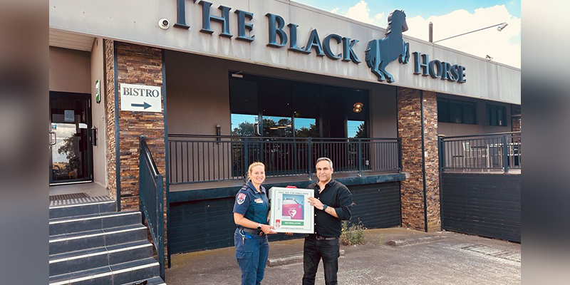 Bulla Heart Safe Community program lead Kathryn Addicott standing in front of The Black Horse Hotel together with hotel manager Rahul Chandhok while holding the new automated external defibrillator device. 