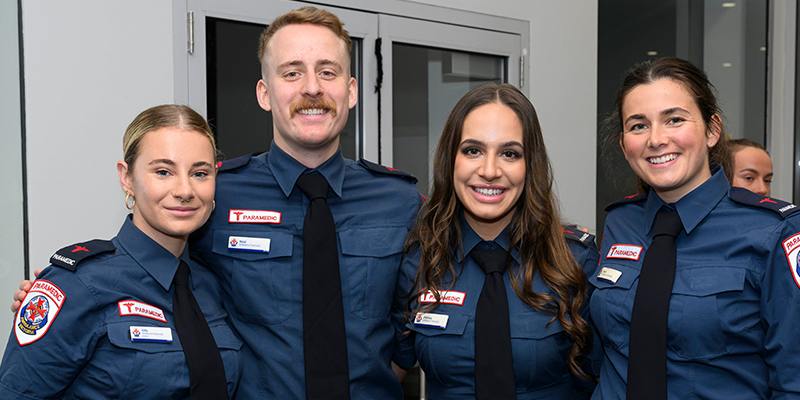 Four paramedic graduates smiling as they celebrate their graduation.