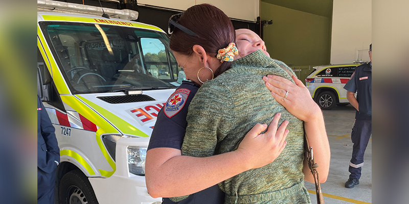 Astrid hugging paramedic Fran Nadin tightly in front of an ambulance.