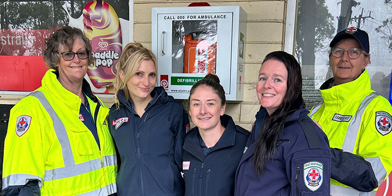 Several Ambulance Victoria Community Emergency Response Team members standing in front of the newly installed automated external defibrillator device.