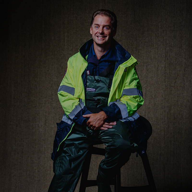 A portrait of Ambulance Victoria Paramedic Educator Adrian Pensak with the waders he wore during the October 2022 floods.