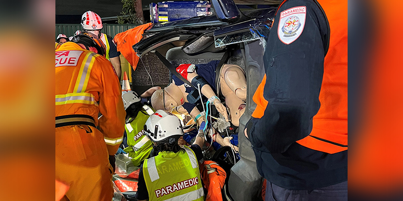A group of first responders treating a manikin in a wreckage of a vehicle.