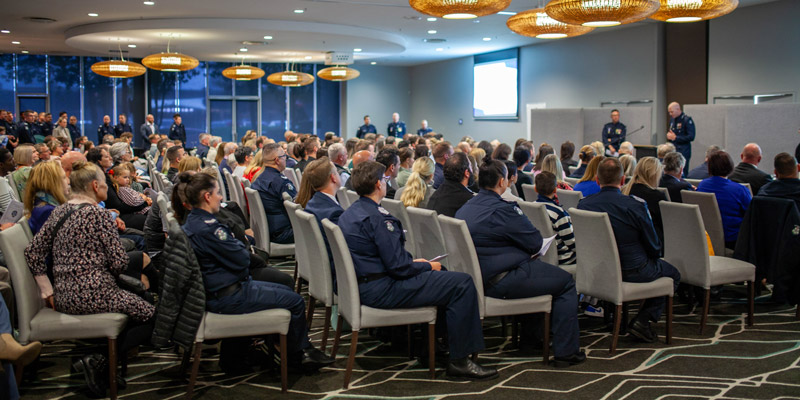 A crowd of people sit in a conference room for an award ceremony