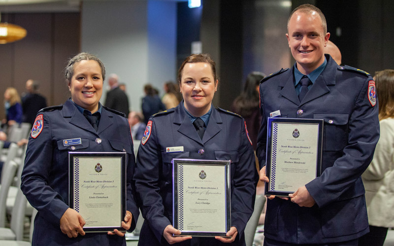 Three paramedics stand holding certificates