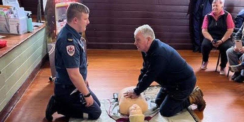 Ambulance Community Officer Brodie teaching a local man on how to perform CPR.